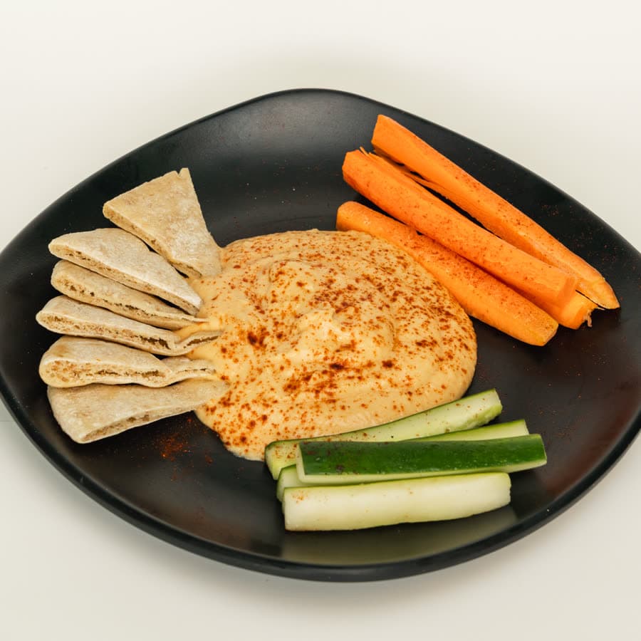 Hummus dusted with paprika, pita bread, carrot and cucumber sticks