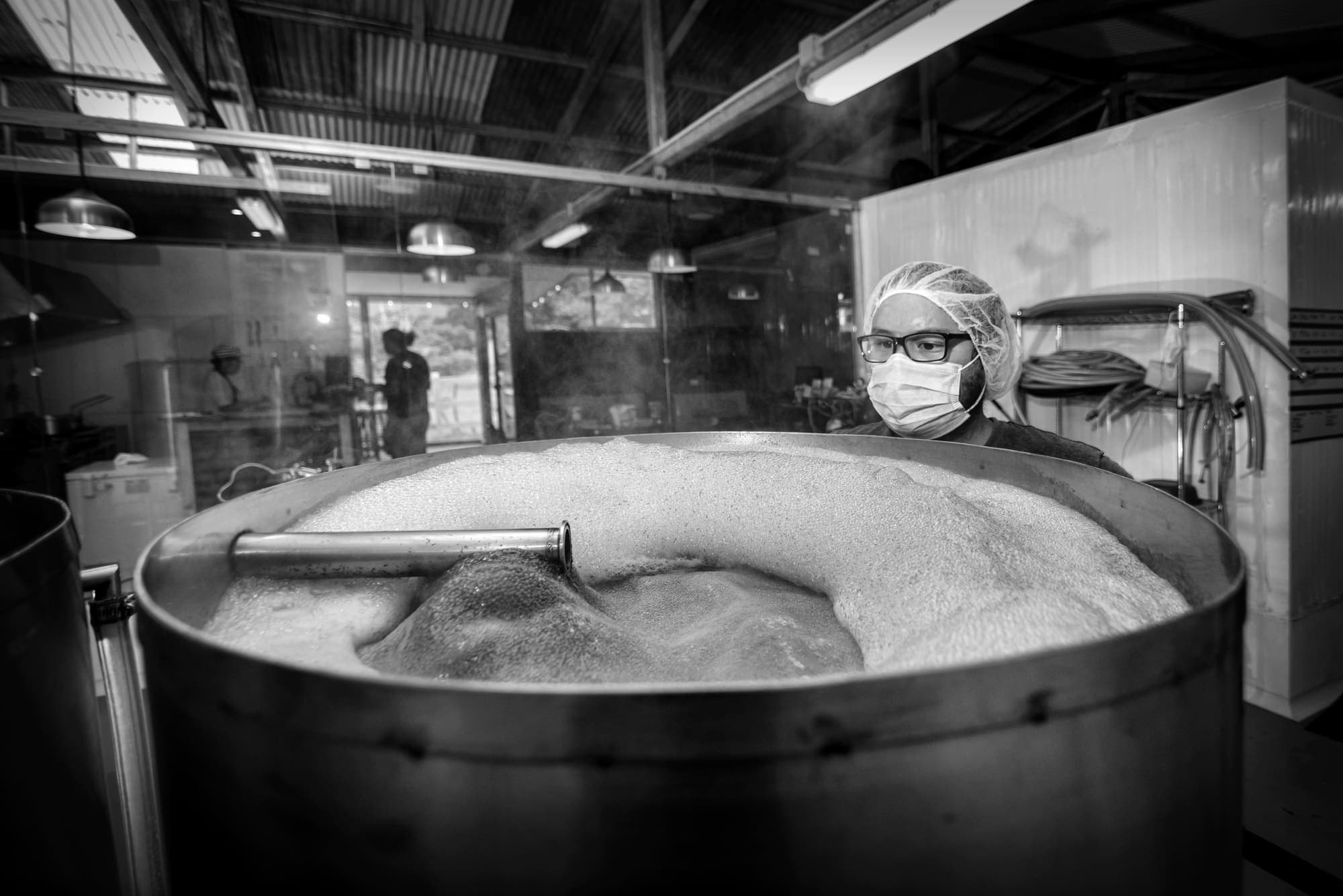 A brewer behind the mash tun, covered in foam