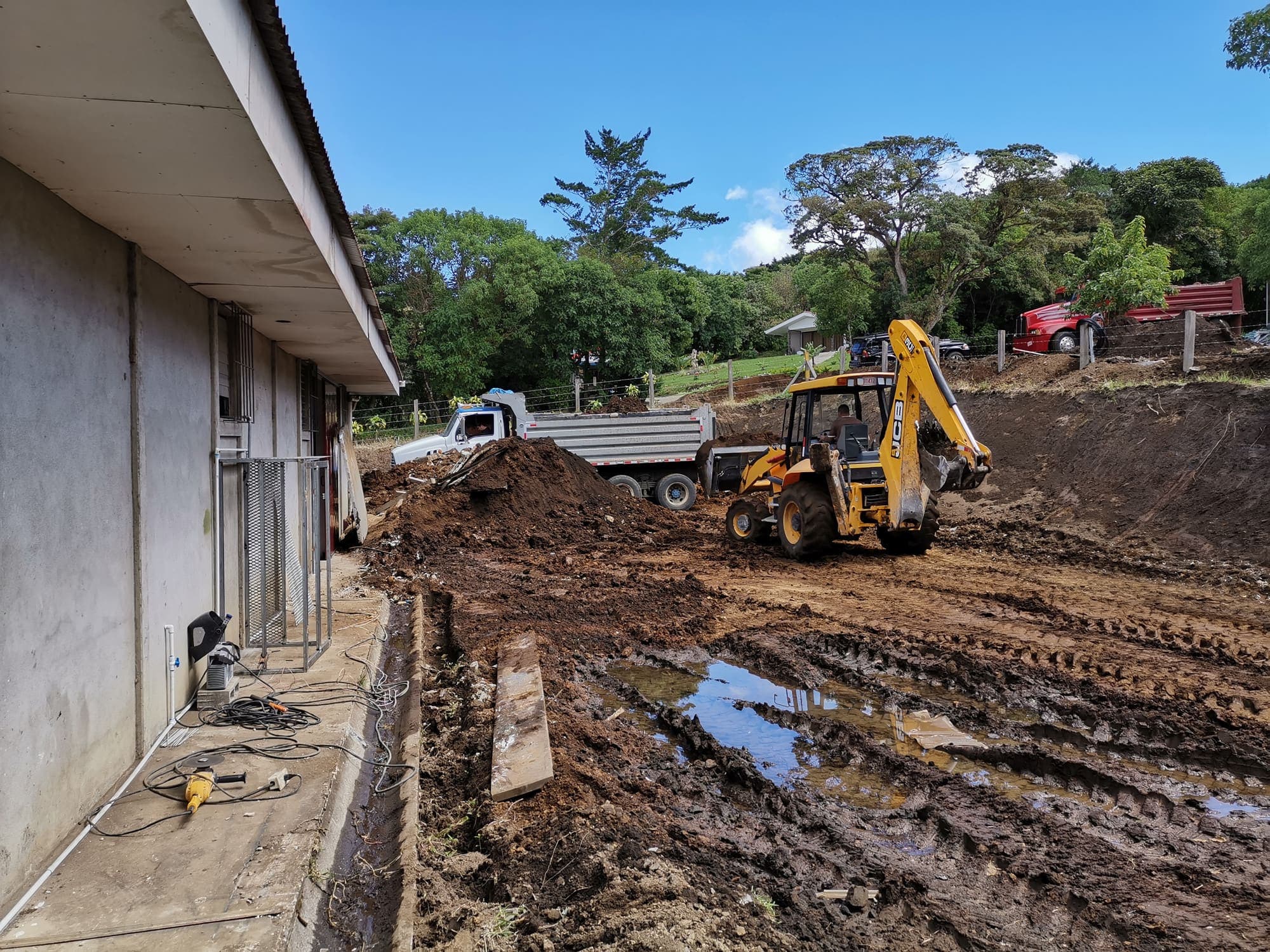 A digger opening a trench alongside the building