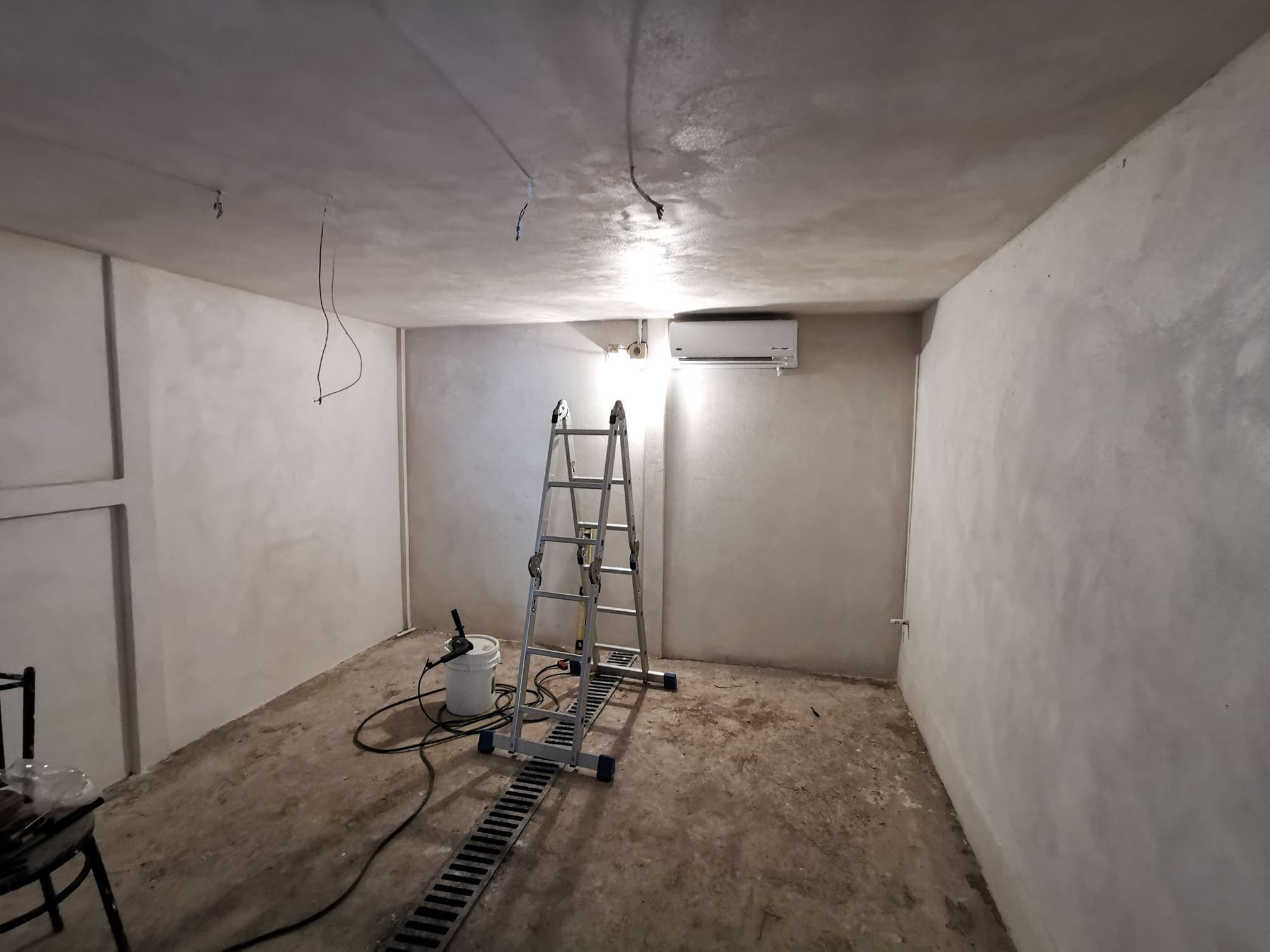 The room plastered, ladder and hanging light still in place