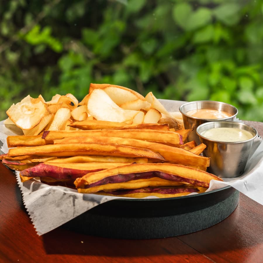 A basket of cassava and sweet potato chips with dips