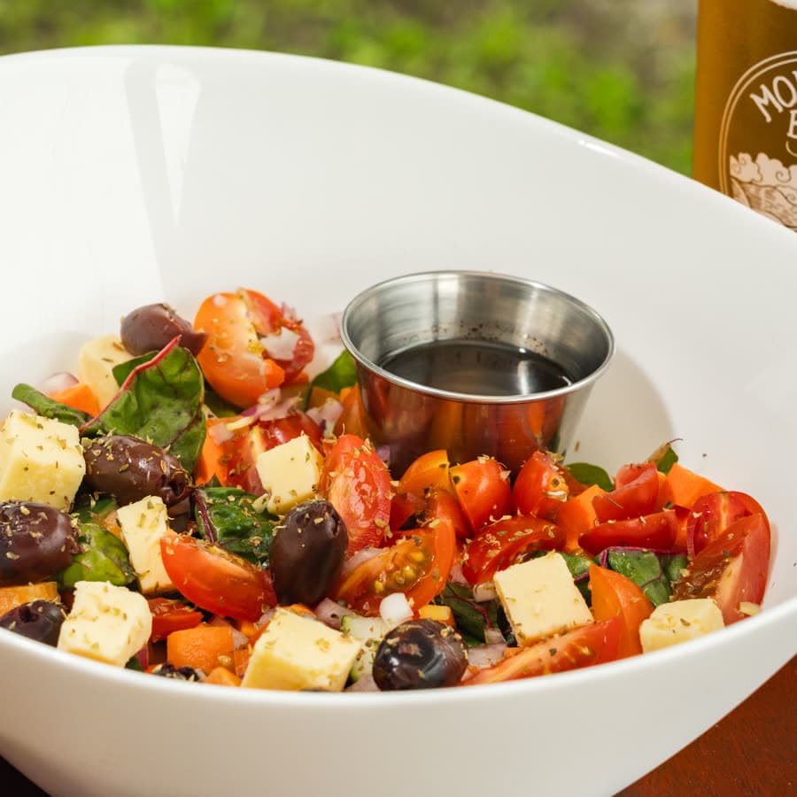 Greek salad with tomato, olives and cheese, in a white bowl
