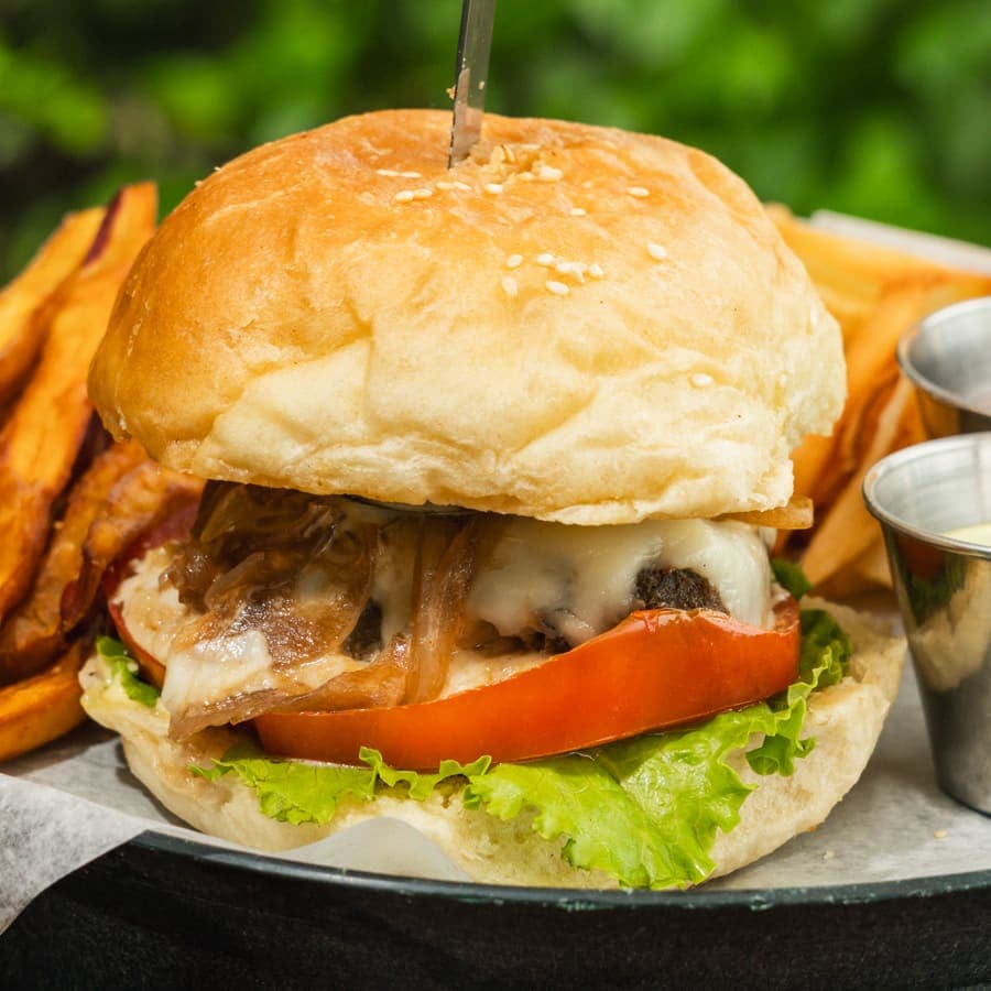 Beef burger with caramelized onion, melted cheese, tomato and lettuce