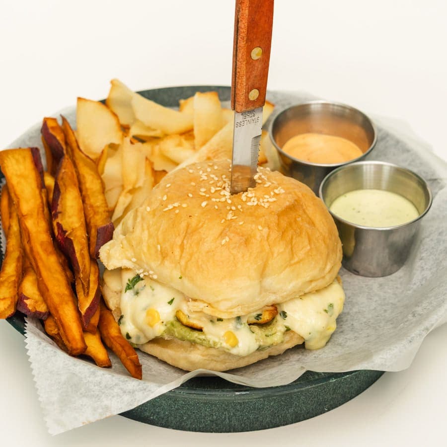 Grilled chicken breast burger with guacamole and creamed corn, with fries