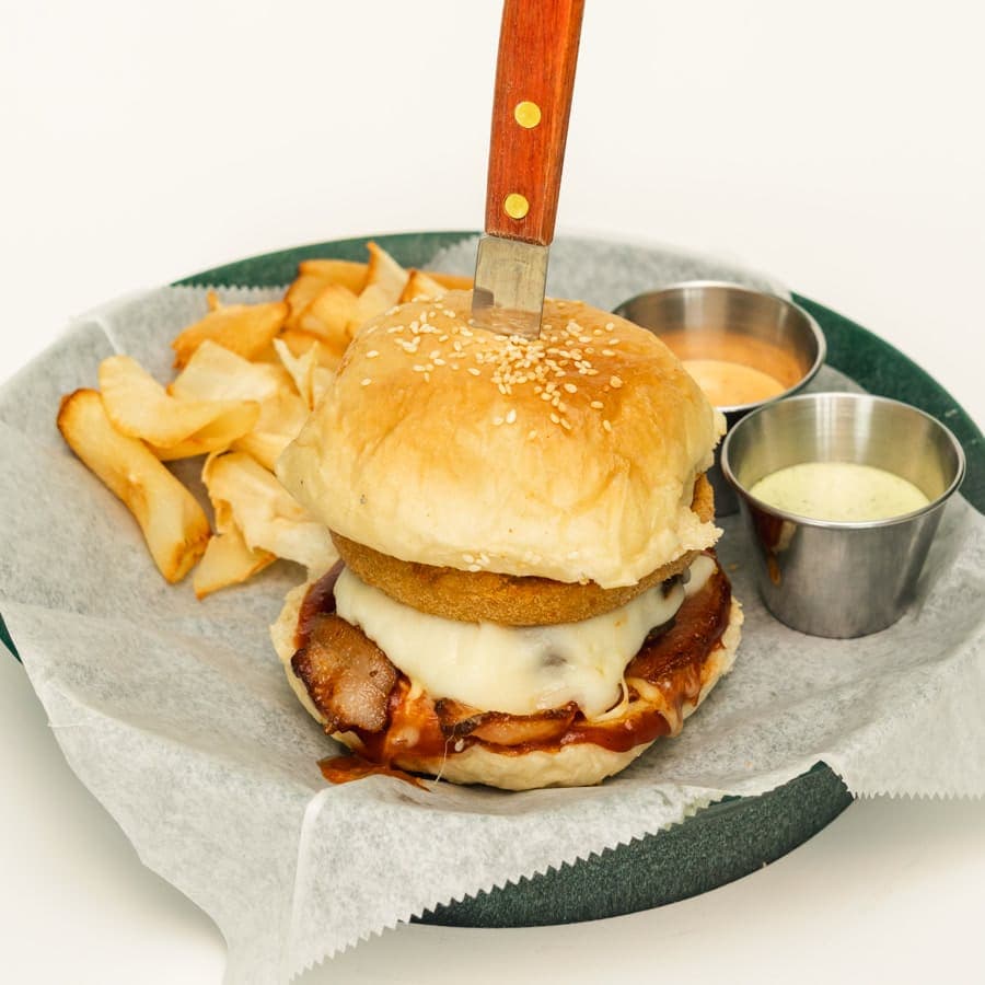 Burger topped with a breaded onion ring, bacon and BBQ sauce