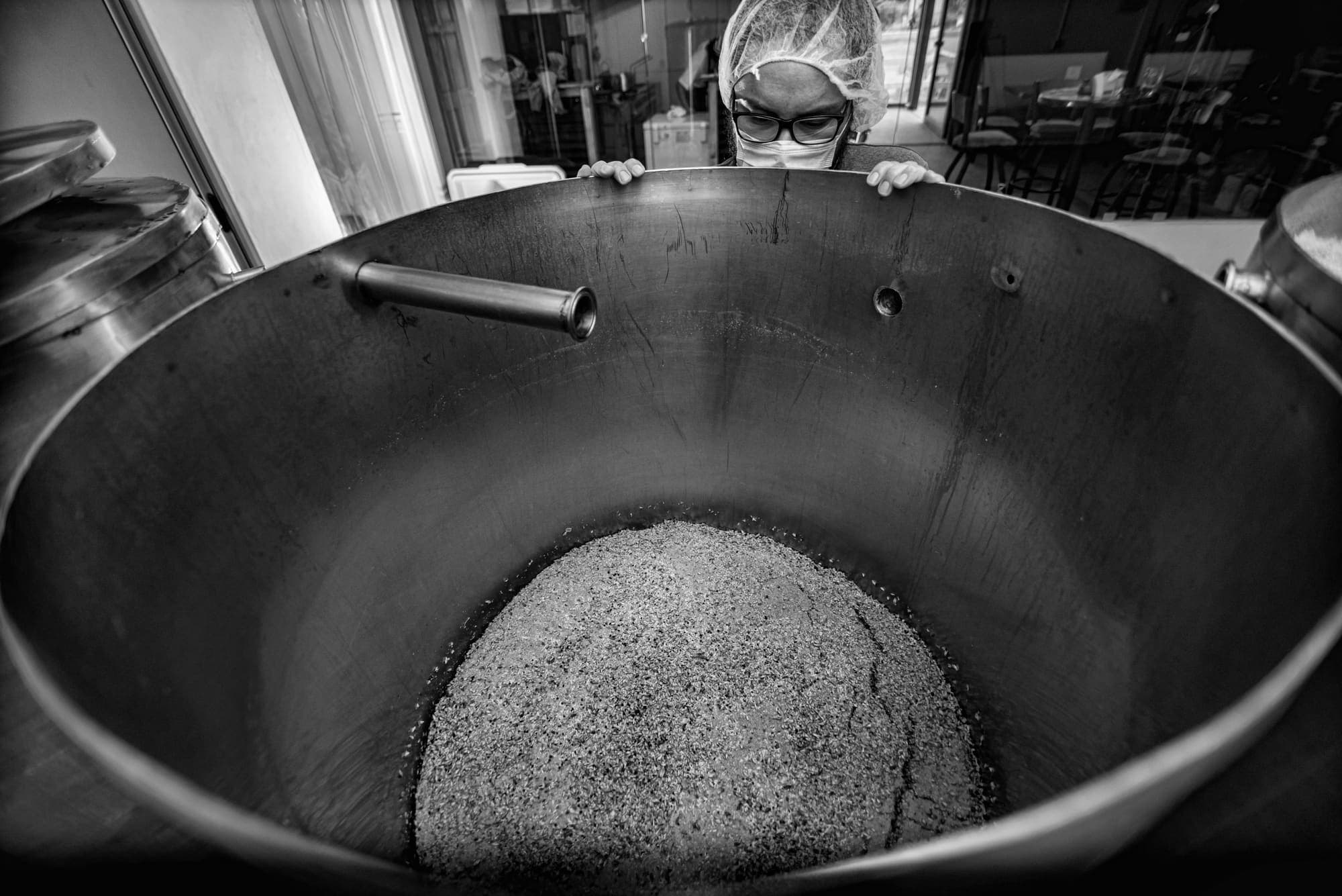 Milled grain at the bottom of the empty kettle, the brewer peering over the rim