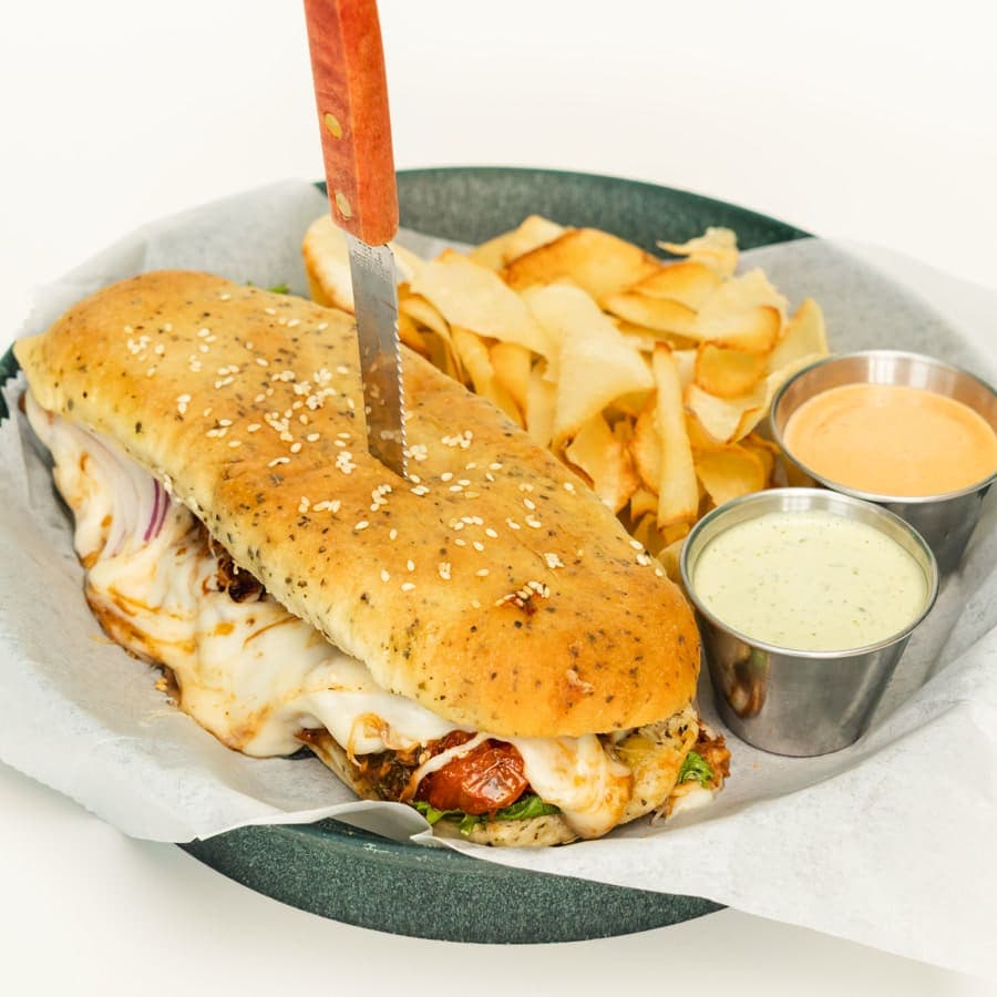 Shredded beef sandwich with melted cheese and red onion, with chips