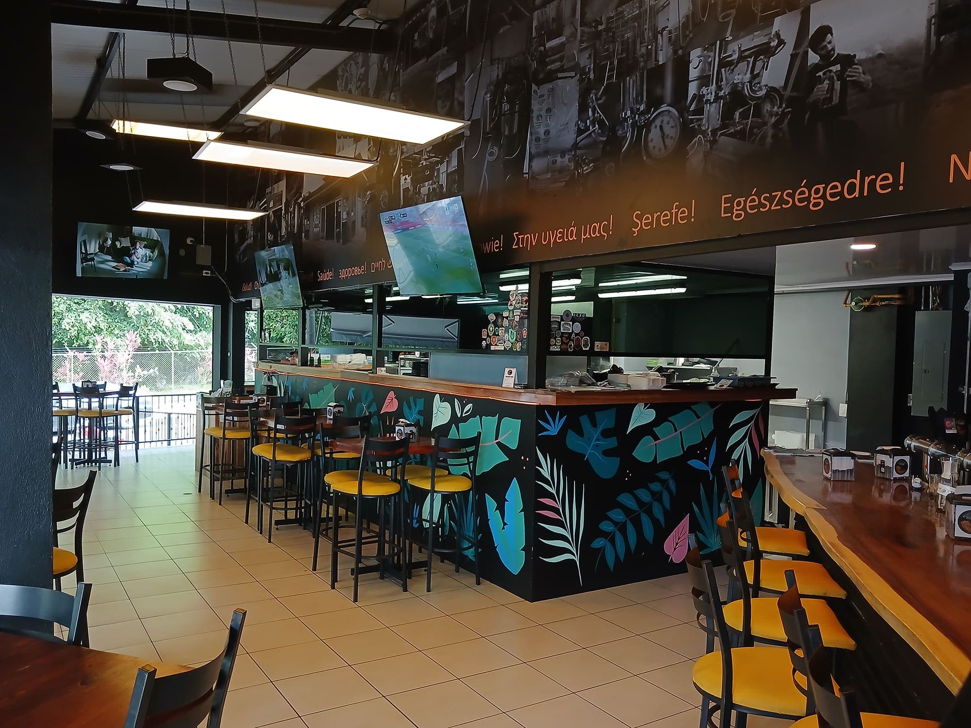 The bar of the La Fortuna taproom beneath the leaf mural