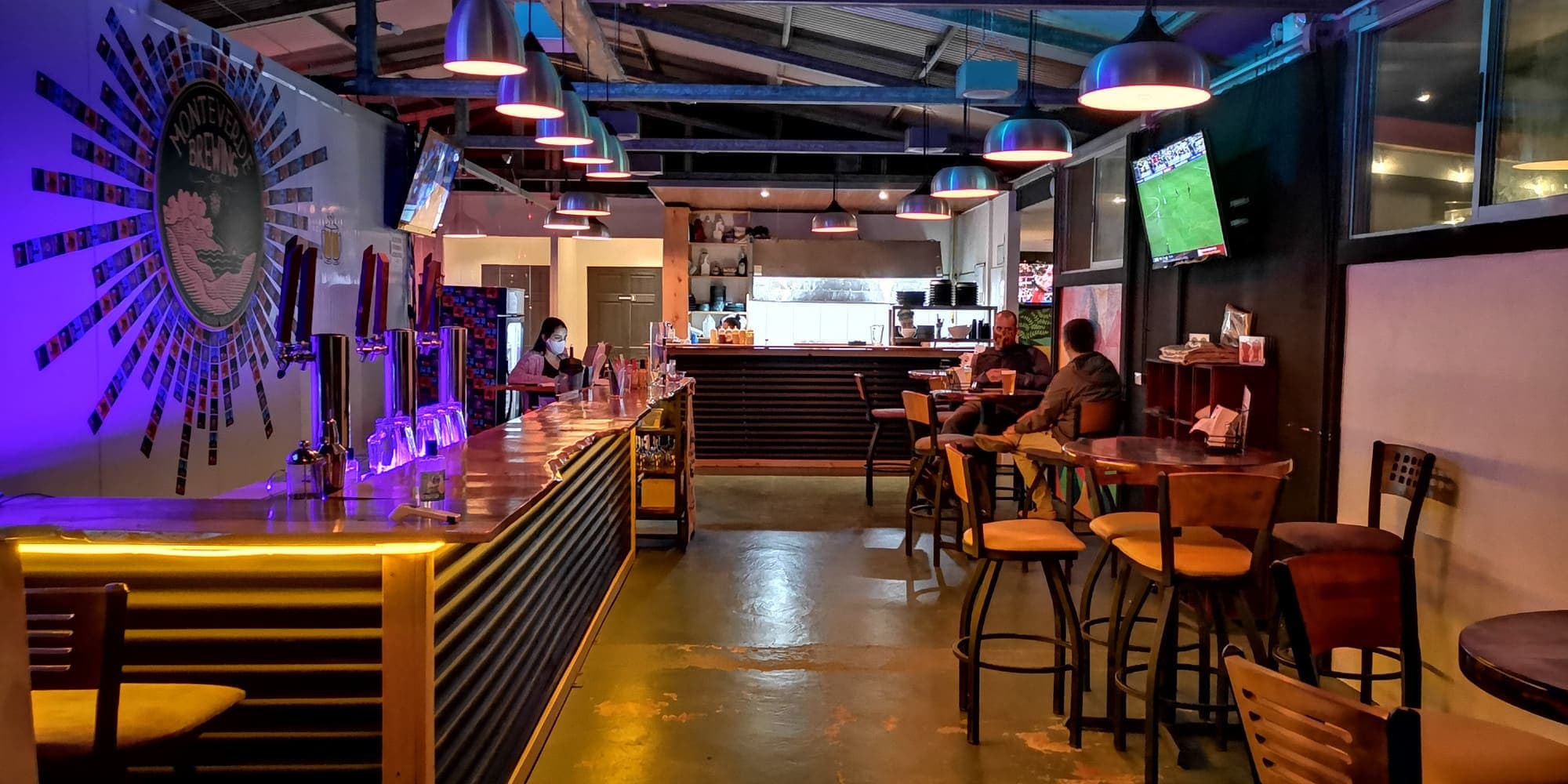 Inside the Monteverde Brewing Company brewpub: the lit bar and the high tables